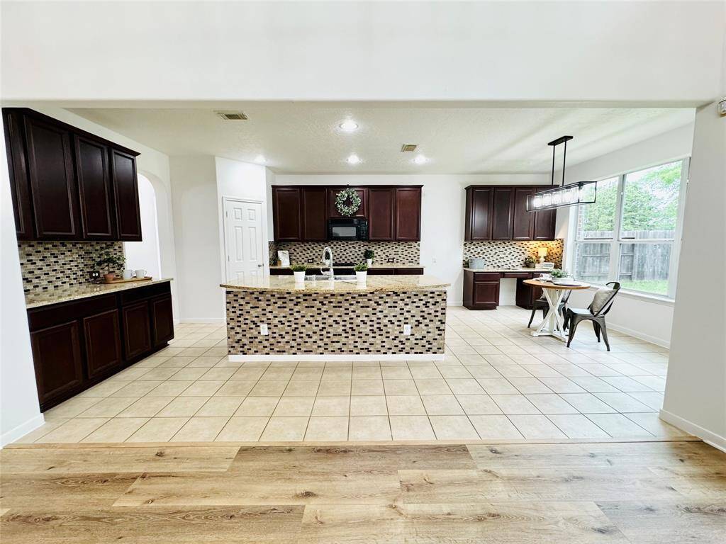 This spacious kitchen is adjacent to your family room! It has 42" warm wood cabinetry, a central granite island with kitchen sink, tile accents, and recessed lighting!