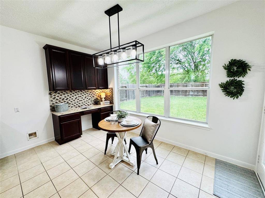 The breakfast room off of the back of the house has large double pane Low E windows overlooking a lush backyard. Your kitchen storage continues with warm wood 42" cabinetry, a stylish tile backsplash, built-in desk and modern light fixture. Make your mornings so special here!