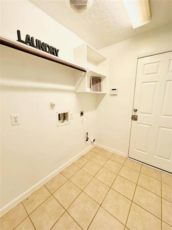 The well-lit laundry room with garage access has tiled flooring, built-in shelving, and hookups for your washer and dryer!