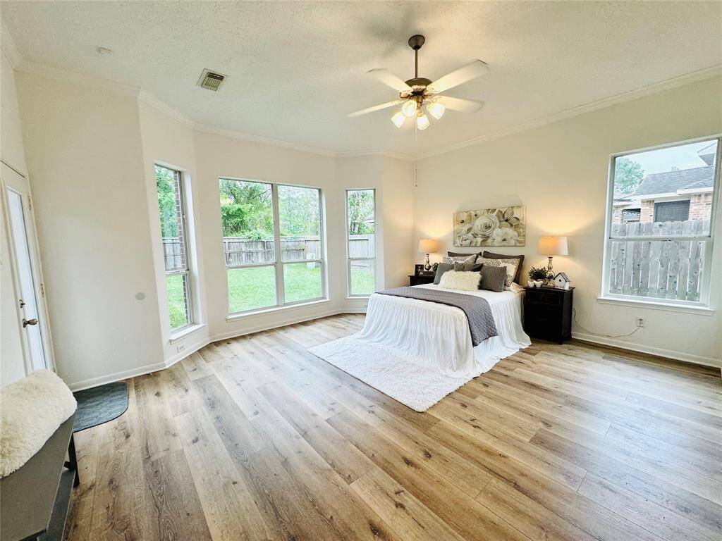 The Owner Suite features a huge room, large bay window offering abundant natural light, a ceiling fan with light, updated LVP wood flooring (2024), double pane Low E windows, and updated wall and trim paint (2024)! The neutral color palette and ample space create a serene and inviting atmosphere.