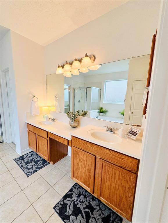 The Owner Bathroom features a double vanity with ample counter space and oak wooden cabinets. It has a large mirror, stylish lighting, and tiled flooring, so you will have plenty of space to get ready each day!