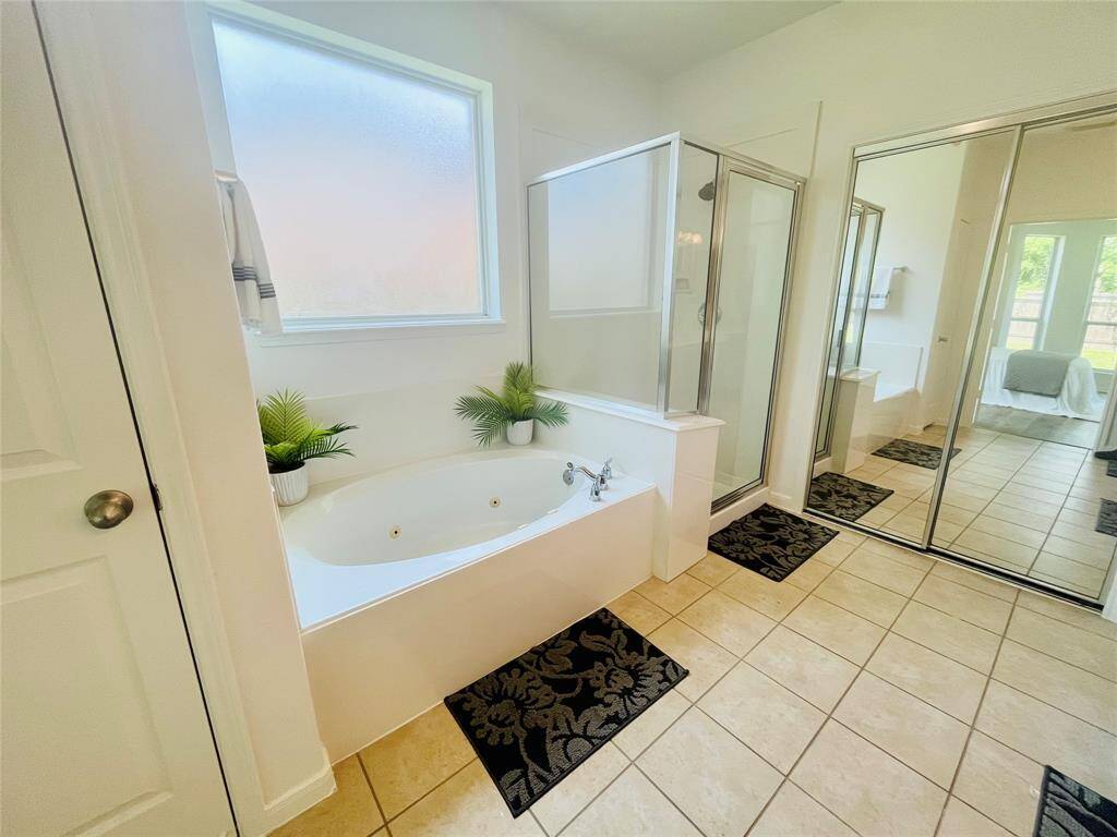 This spa-like bathroom features a spacious layout with a linen closet, a large jetted tub, separate glass-enclosed shower, and dual sinks. It is well-lit with natural light from a frosted window for privacy! There is a large closet for you through the double doors!