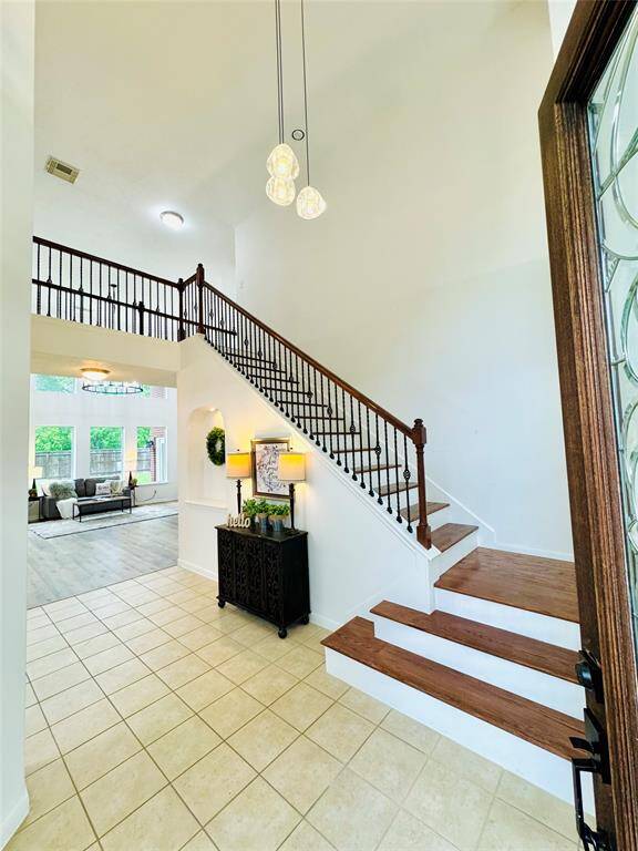 See the soaring two story entryway with high ceilings and elegant staircase with oak banister and black metal ballusters! The tiled floor leads to a bright living area with large window and gorgeous views!
