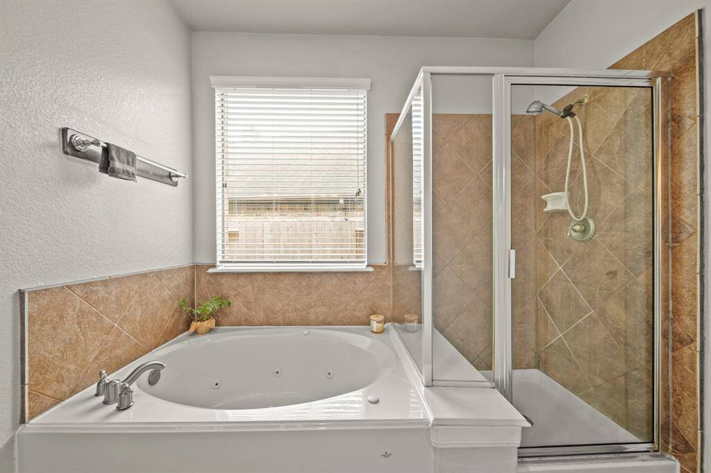 It is complete with a large garden style tub, a beautiful walk-in shower with a gorgeous tile shower wall, and a large window with privacy blinds providing natural light.