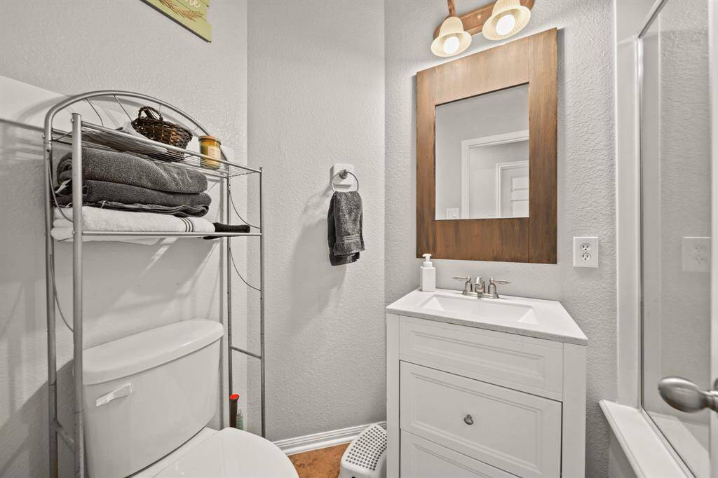 Secondary bathroom with tile floors and a framed mirror.