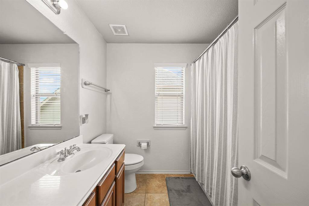 Secondary bathroom with tile floors, granite countertops and backsplash, a large mirror and a window with privacy blinds.