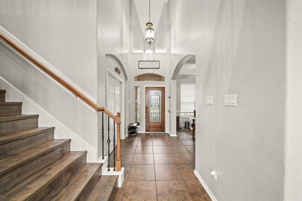 Check out the charming staircase with wood steps, and the pendant lighting off the high ceiling in the foyer.