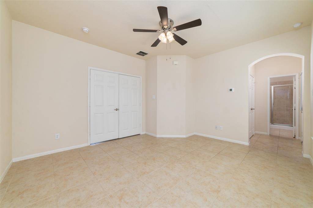 Large first floor en-suite bedroom equipped with tile flooring and ceiling fan.