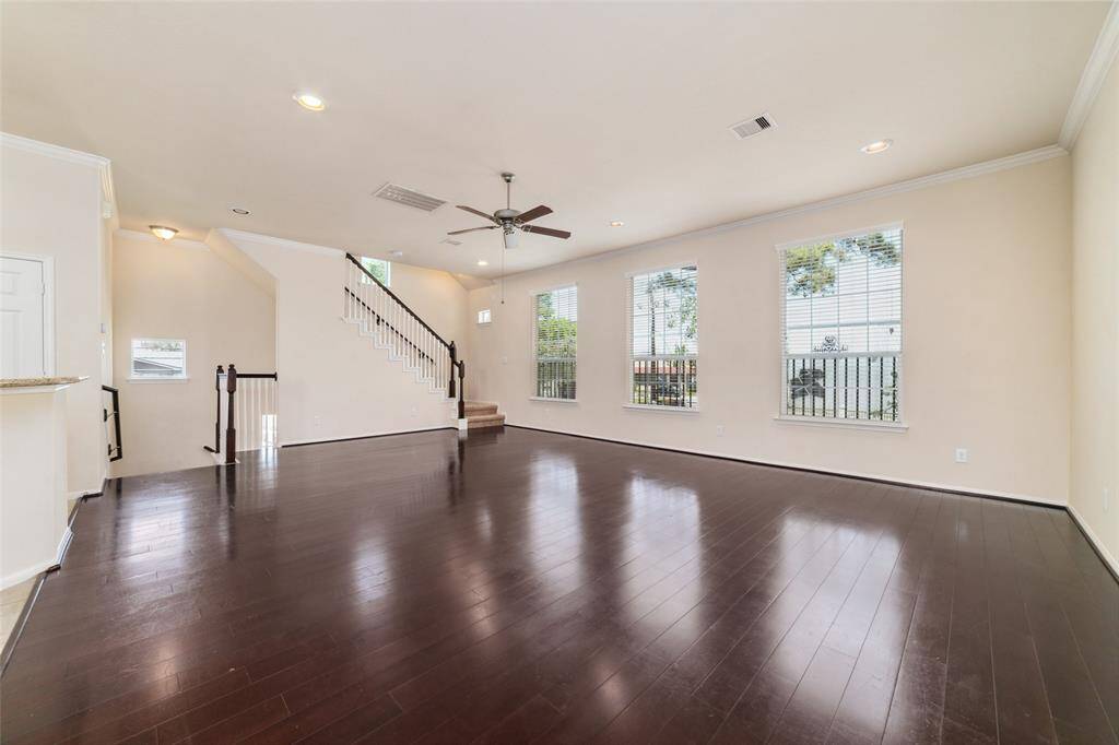 Second floor features spacious open main living area with large windows, recessed lighting, wood flooring.