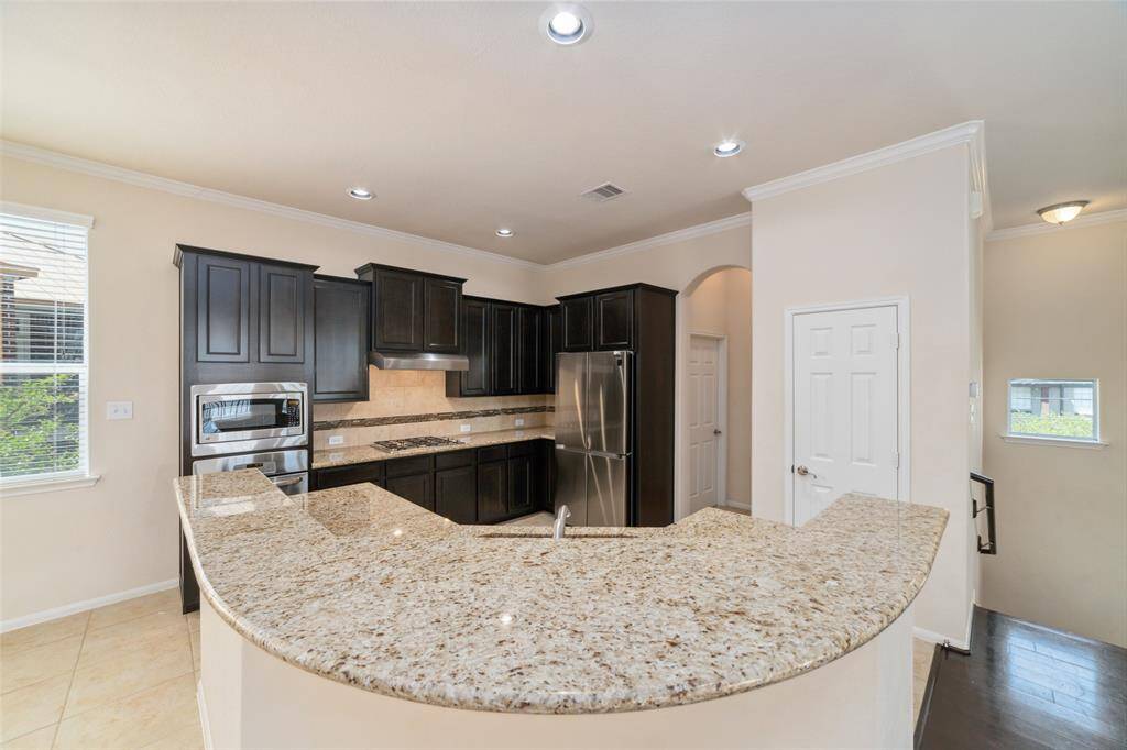 Large crescent shaped granite breakfast bar to invite you into the gourmet kitchen.