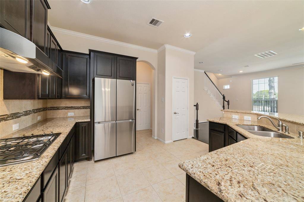The kitchen features granite countertops, stainless steel appliances, gas range, and dark wood shaker cabinets for storage.