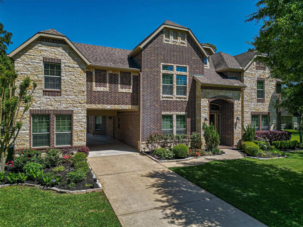 This is a spacious two-story home with a blend of brick and stone exterior, featuring a covered entrance and a well-maintained front yard with landscaping. It includes a driveway and has a modern, elegant appearance.