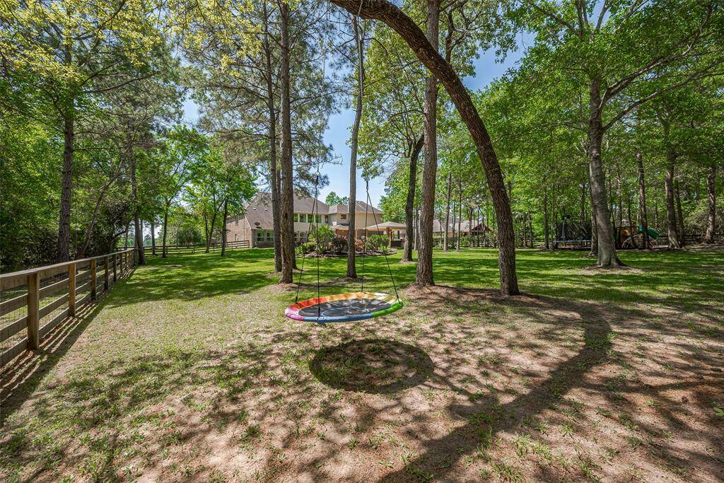 Spacious 1 acre backyard with mature trees, a swing, and a fenced perimeter, offering privacy and a family-friendly atmosphere. Ideal for outdoor activities and relaxation.