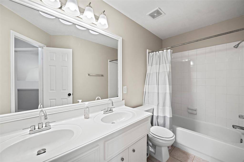 A full-sized bathroom boasts dual vanity sinks with cabinets for storage, and a shower/tub combination with tile surround that is so easy to maintain!