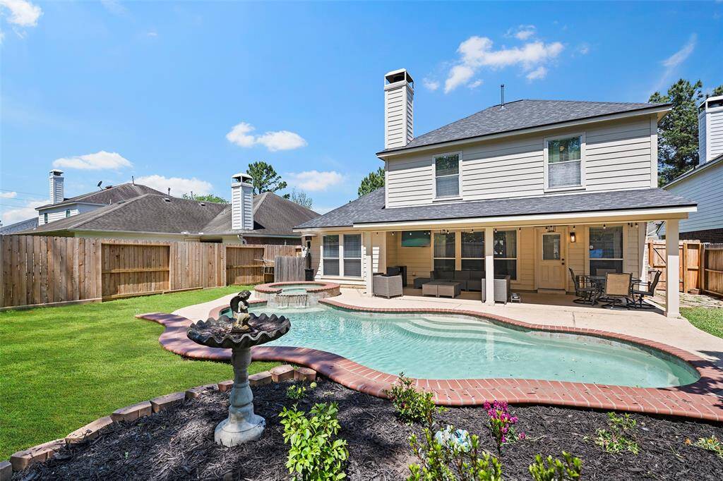 A large flowerbed with blooming foliage, along with the sparkling pool and large covered patio area, with plenty of greenspace for Fido to run and play too!