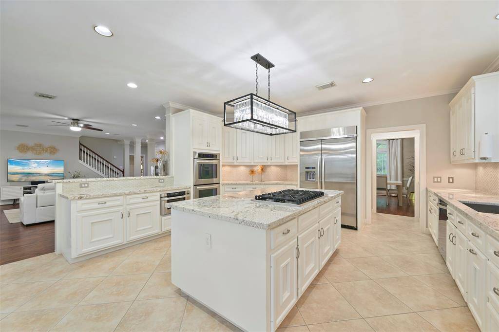 This spacious Chef's kitchen with custom detail features elegant white cabinetry, exotic granite countertops, built-in refrigerator, double convection ovens, under cabinet microwave, large walk-in pantry, and a Viking 6-burner gas cooktop. Kitchen seamlessly opens to the cozy Family room, and is also connected to the Formal dining room through the Butler's pantry, ideal for entertaining.