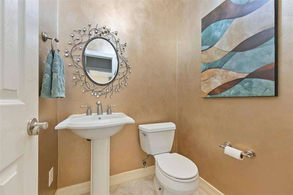 This charming guest powder room on the first floor features a classic pedestal sink that adds timeless elegance to the space. A stylish mirror enhances the room's bright and welcoming atmosphere, while the neutral tones and updated fixtures provide a clean and polished look.
