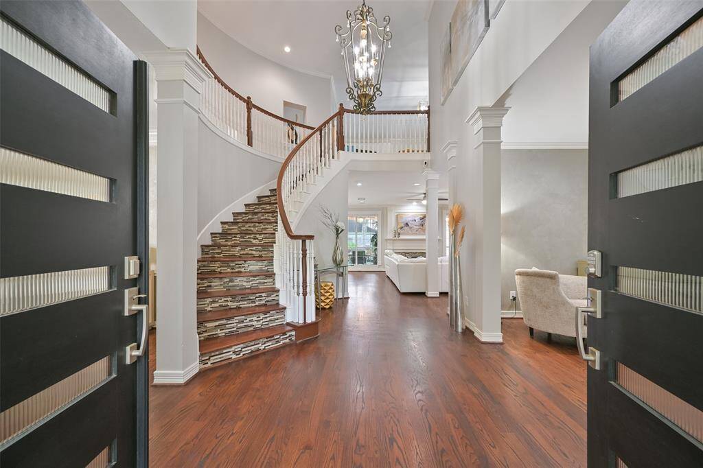 Double custom doors welcomes you to this elegant foyer featuring a grand curved staircase, 2-story entry, with a stunning chandelier. The open layout leads to a spacious formal living and dining areas with engineered hardwood floors, creating a welcoming and luxurious entrance.