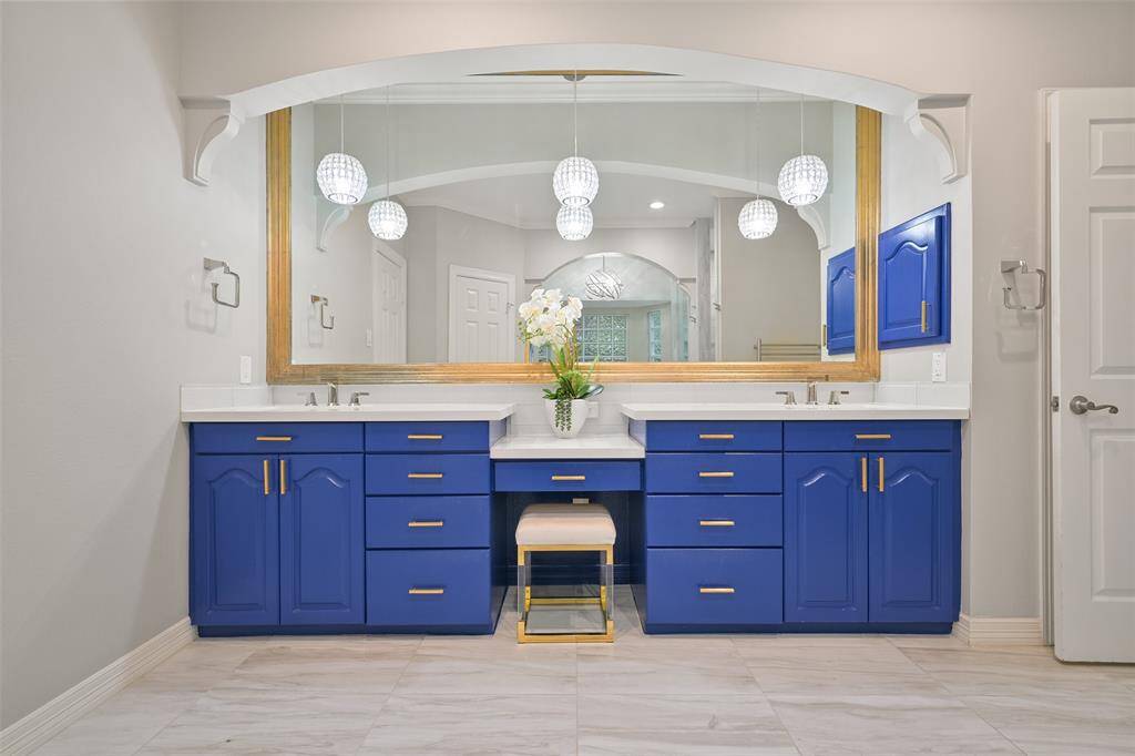 This luxurious and modern Primary bathroom features dual sinks with vanity, and a large, framed mirror. Elegant pendant lighting and a stylish vanity area add a touch of luxury.