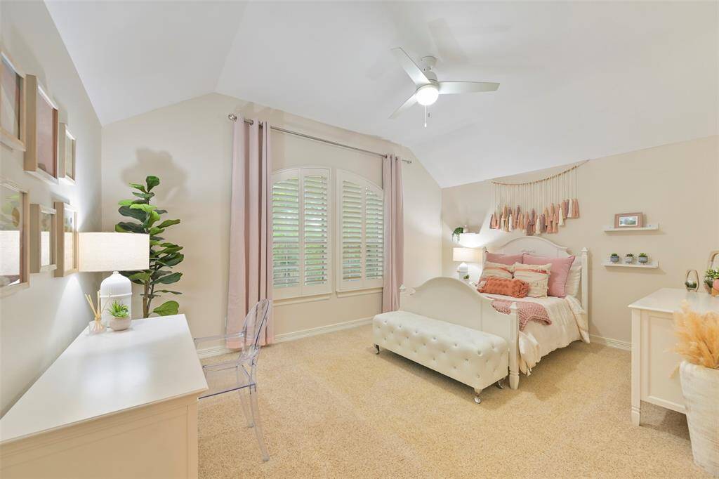 Another spacious secondary bedroom on the second floor is bright and inviting featuring a vaulted ceiling, large walk-in closet, and soft neutral tones. This room also features plush carpeted flooring, a wall of windows with plantation shutters overlooking the front, bringing natural light. This room is perfect for comfort and relaxation.