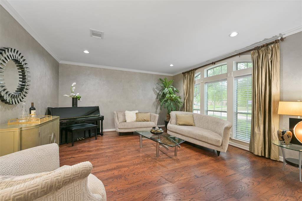 Bright and elegant formal living room with large windows overlooking the front yard, hardwood floors, and neutral colors creating a cozy and inviting atmosphere.