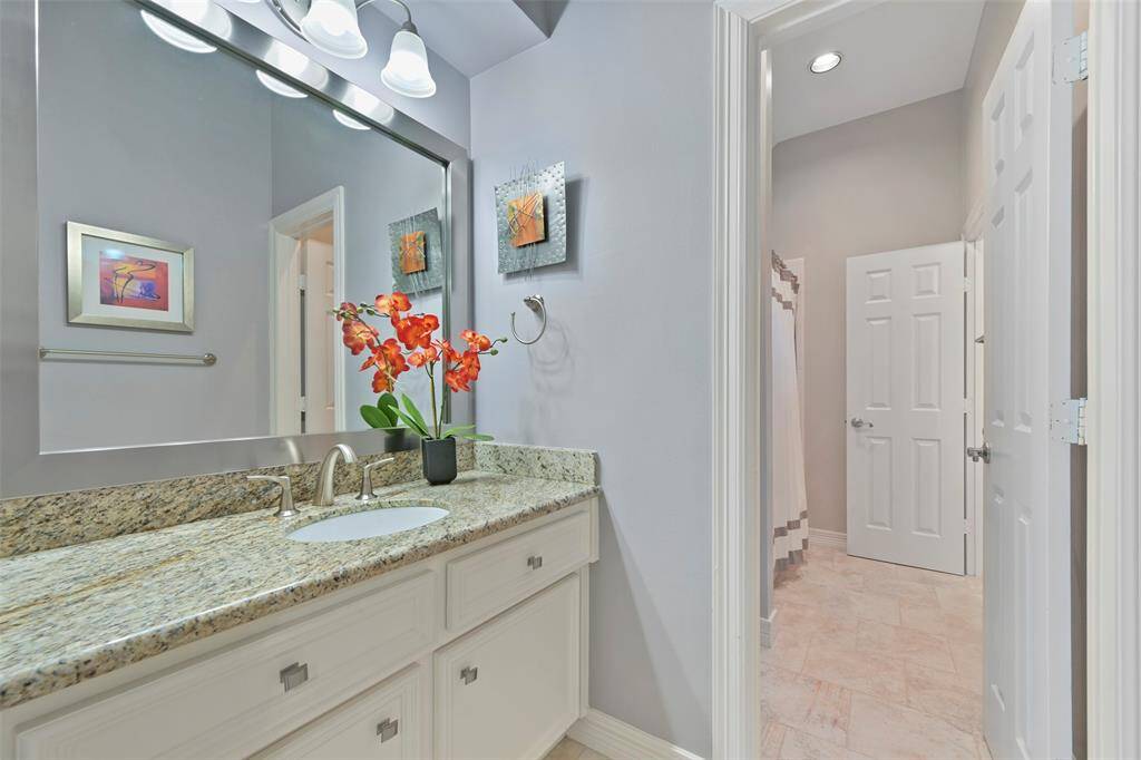 The other sink area for the Jack and Jill bathroom featuring an expanded counter with granite countertop, a single sink, a large mirror, and modern light fixtures. The neutral walls and tile flooring create a clean, spacious feel.