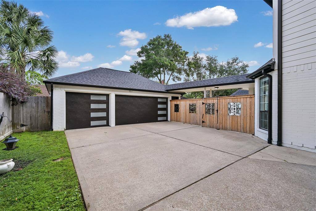 The spacious, oversized 3-car garage showcases a custom garage door and built-in cabinetry for additional storage. An automatic gate and additional parking space complete this functional and secure area.