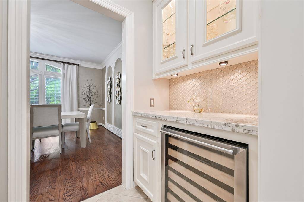 A butler's pantry seamlessly connects the formal dining room to the kitchen, featuring a wine fridge and elegant glass-front upper cabinets.