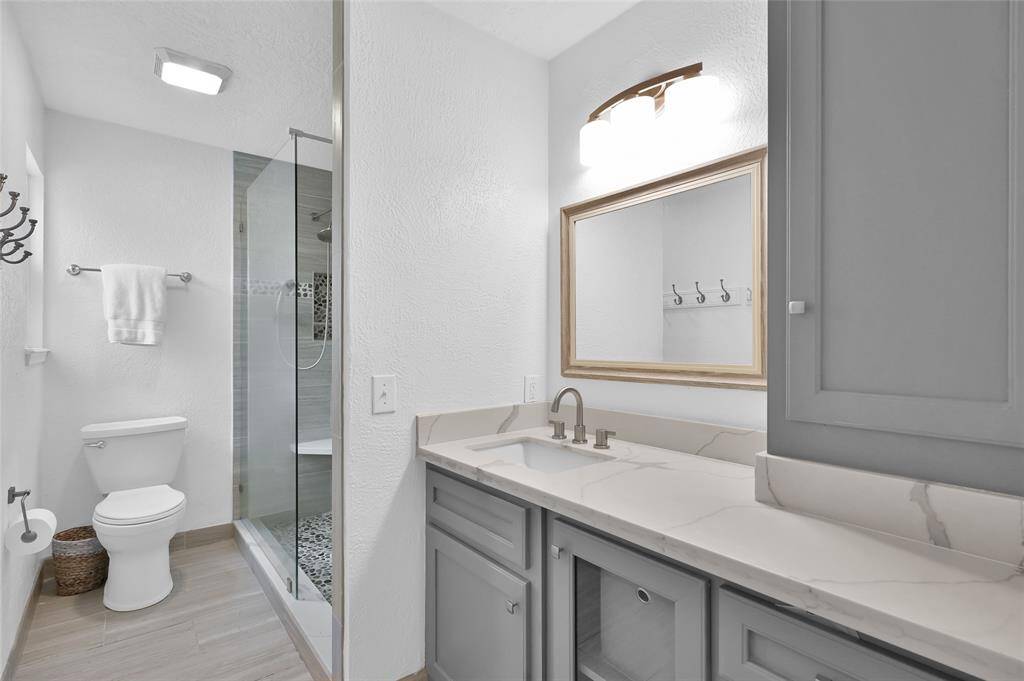 The remodeled Primary Bathroom has a granite countertop with painted wood cabinets/drawers and storage tower, chrome faucet and updated mirror and light fixture.