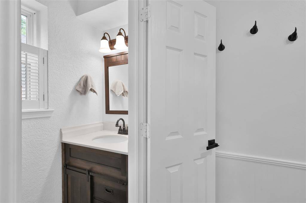 A Half-Bath is located off the Kitchen and Laundry Room with an oil-rubbed bronze faucet, updated light fixture and framed mirror.