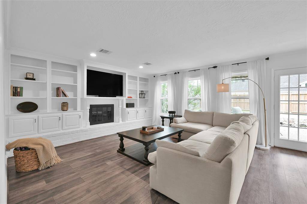 Enjoy gathering in the Living Room with a gas log fireplace, painted brick and hearth surround and built-in shelving & cabinets flanking the fireplace.