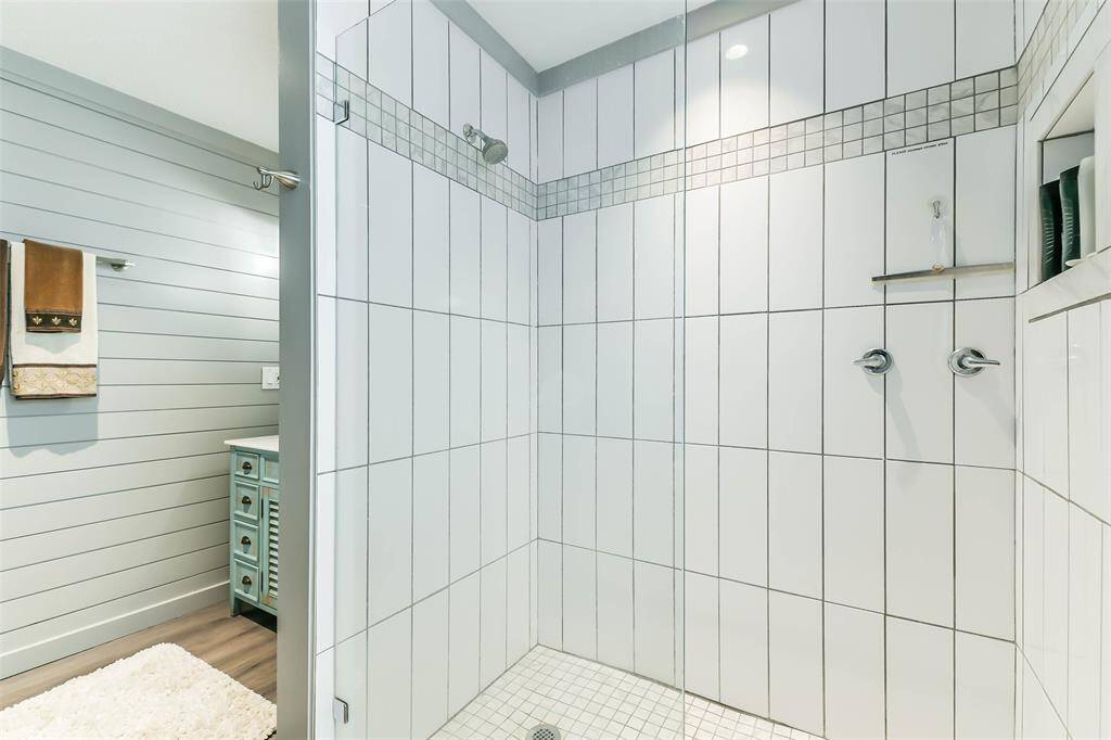 A ceramic tile shower enclosed by a sleek glass door.