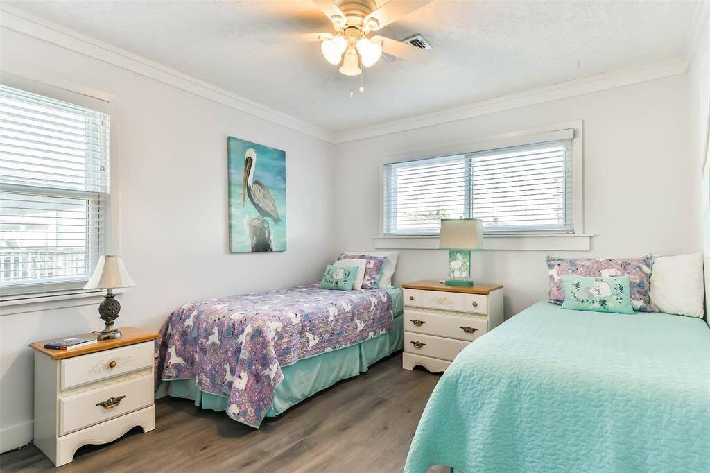 Bedroom #3 with crown molding, two inch blinds, two windows and a ceiling fan with light fixture.