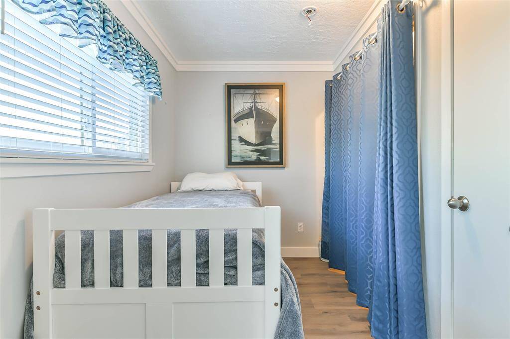 A laundry room featuring a daybed, elegant crown molding, and two-inch blinds.