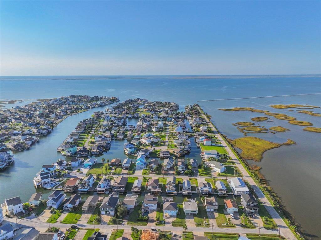 Aerial view of a home, featuring wetlands on the right and the bay in the background.
