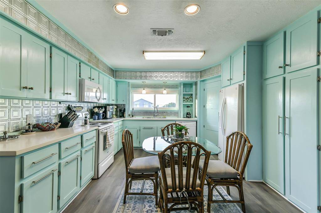 The kitchen boasts stunning white quartz crystal countertops, a stylish tin backsplash, and drawers that close softly for added convenience.