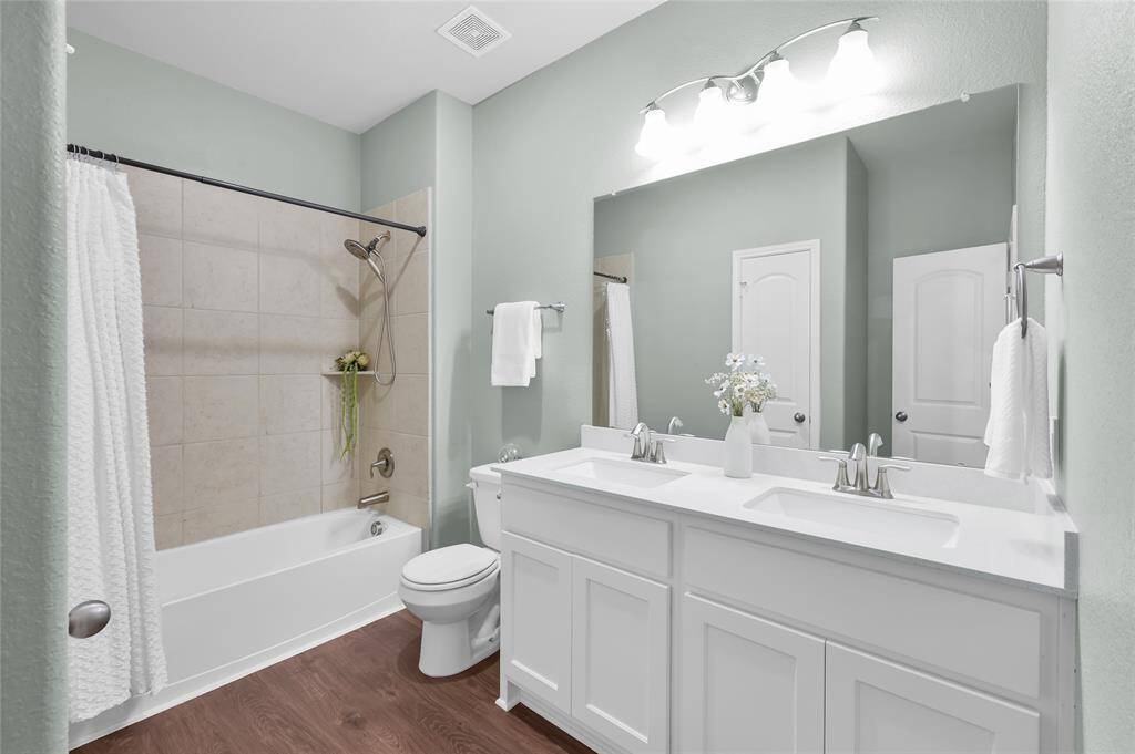 Stylish guest bath with a RARE DOUBLE SINK vanity, modern fixtures, and a tiled shower/tub combo is closely located between the second and third secondary bedrooms.