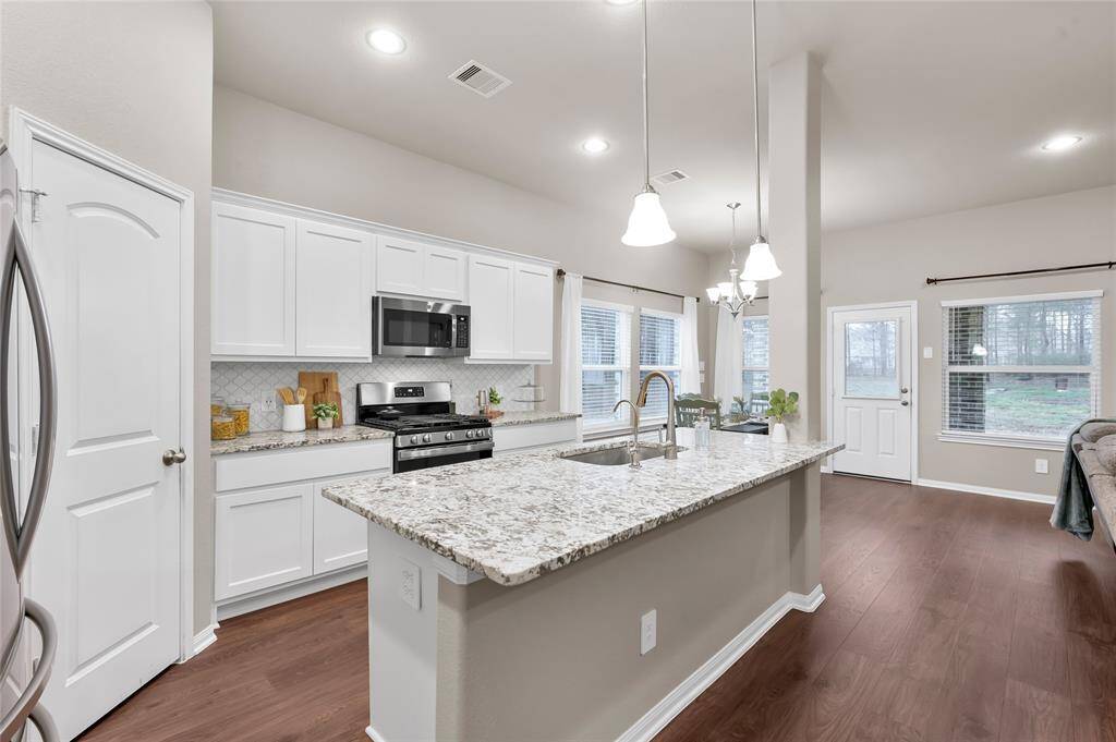 Beautiful kitchen with white cabinetry, a large island, walk-in pantry and arabesque tile backsplash. Treat yourself to tasty water from the AquaKinetic A200 Drinking Water reverse osmosis system located under the sink. It also has a Macrolite Backwashing Filter to reduce certain forms of iron, sediment, particulate matter and more!