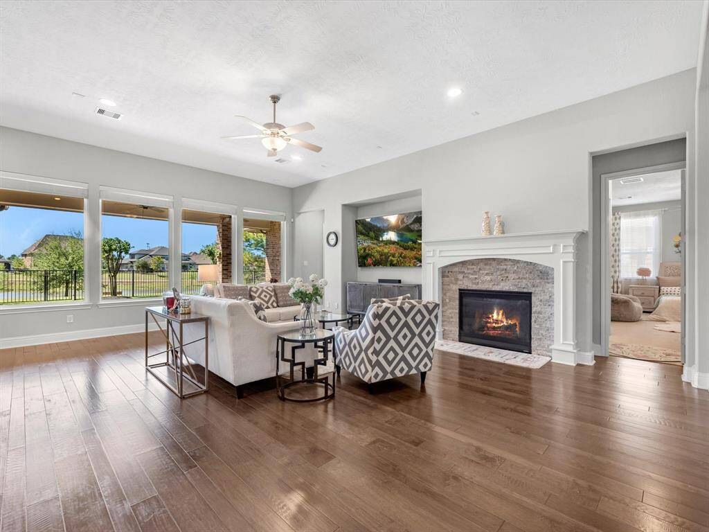 Alternative view of the living room showcasing the stone fireplace with white molding. Imagine cozying up next it during chilly evenings! also beautiful view of the lake.