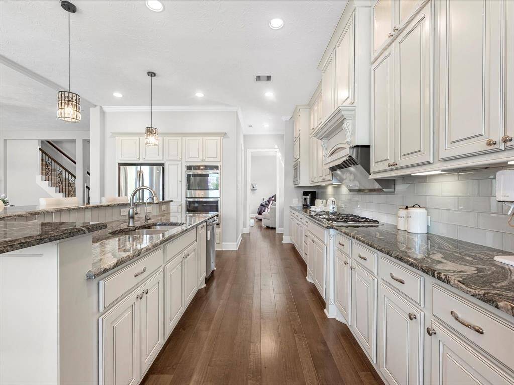 Amazing gourmet island kitchen features white custom cabinets, granite countertops, stainless steel appliances, double oven!