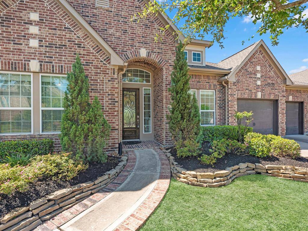 Gorgeous exterior features lush landscaping with stone bordered flower beds complimenting the rich tones of the home.