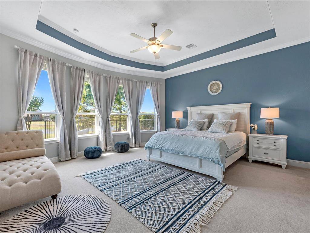 Elegant primary retreat with wall to wall windows allowing views to the beautiful backyard and lake! Custom paint highlights the tray ceiling!