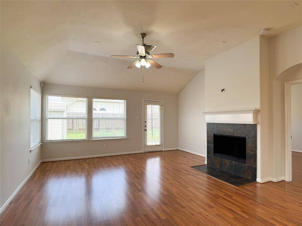 wide open living room w/vaulted ceiling, laminate wood flooring & backyard beyond