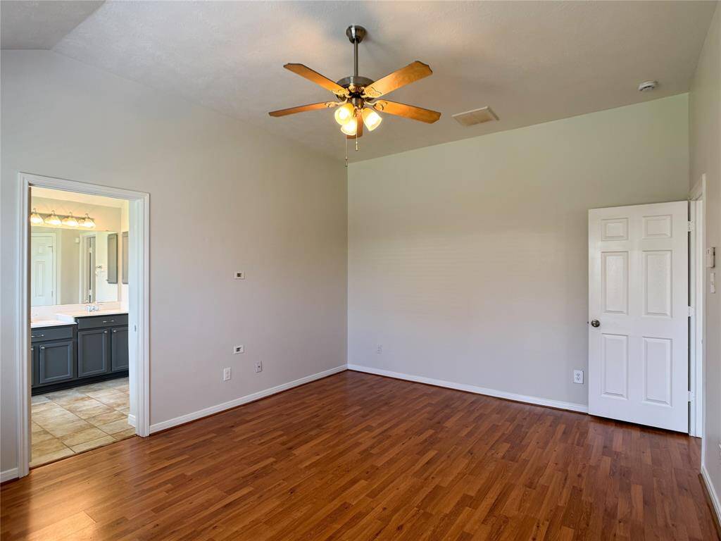 huge primary bedroom w/vaulted ceiling, laminate wood flooring, ceiling fan