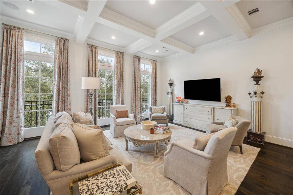 Inside the home exudes sophistication with rich hardwood floors, 10 ft coffered ceilings and custom shutters. Natural light pours in through expansive 8-foot windows creating a bright and airy living space.