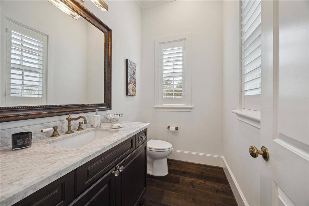 Large half bath off of living area with marble countertops and hardwood floors.