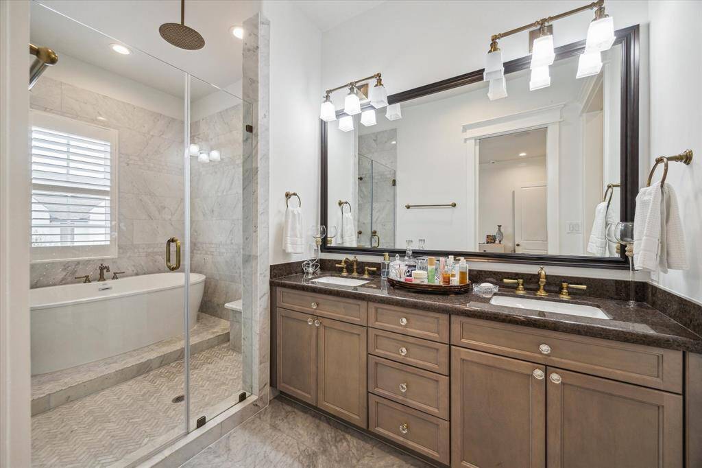 Primary bathroom featuring a freestanding tub,European fixtures and a rainfall shower. The double vanity is adorned with exquisite Carrera marble and Carrera marlble floors, is such a stunning serene atmosphere.