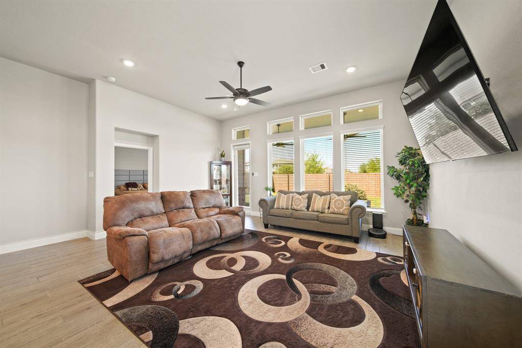 Big windows, sleek fan, and tile floors that mean business. This is where movie marathons happen, where guests feel welcome, and where you finally get to stretch out on *your* couch.