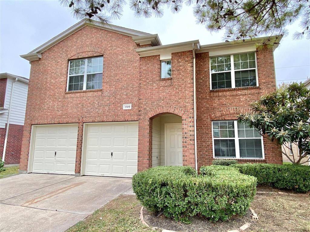 This two-story brick home features a dual garage and a welcoming front entrance. It has large windows for natural light, a well-maintained front yard with shrubs, and a clean driveway. Ideal for a family seeking a comfortable and stylish living space.