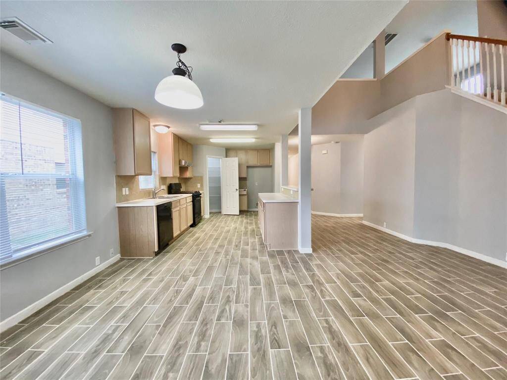 A spacious open-plan kitchen and living area with modern tile flooring, ample natural light, and neutral color walls.